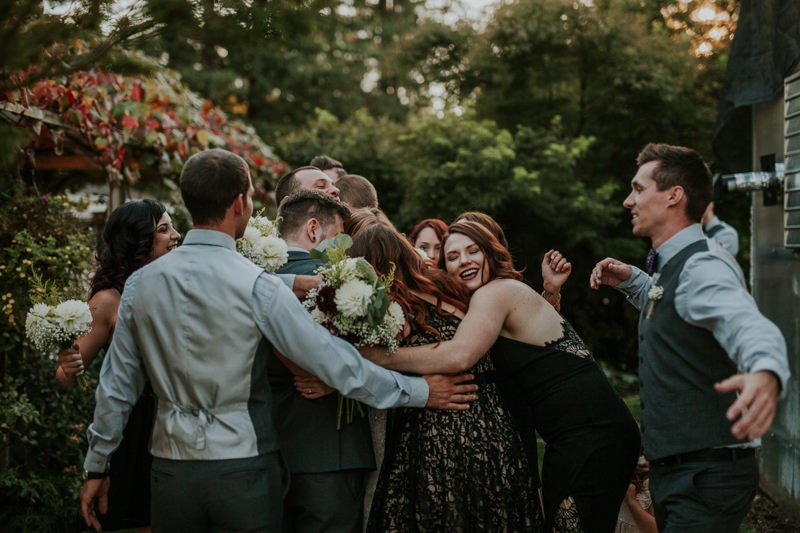 Loving wedding party group hug, after a fun outdoor ceremony. 