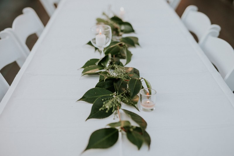 Simple garden wedding reception decor, with greenery, seeded Eucalyptus, and white candles. 