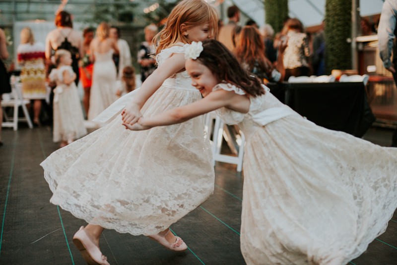 Flower girls in a white lace dresses, dancing with each other. 