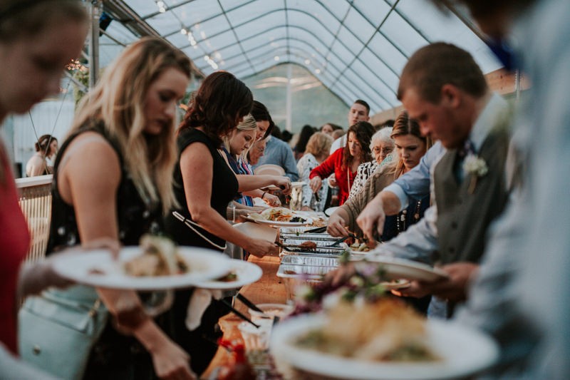 Taco wedding buffet, with guests dishing up, in a greenhouse venue. 