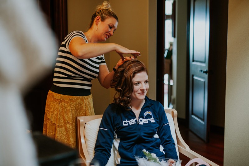 Bride getting ready in-home, with hair stylist creating an up-do. 