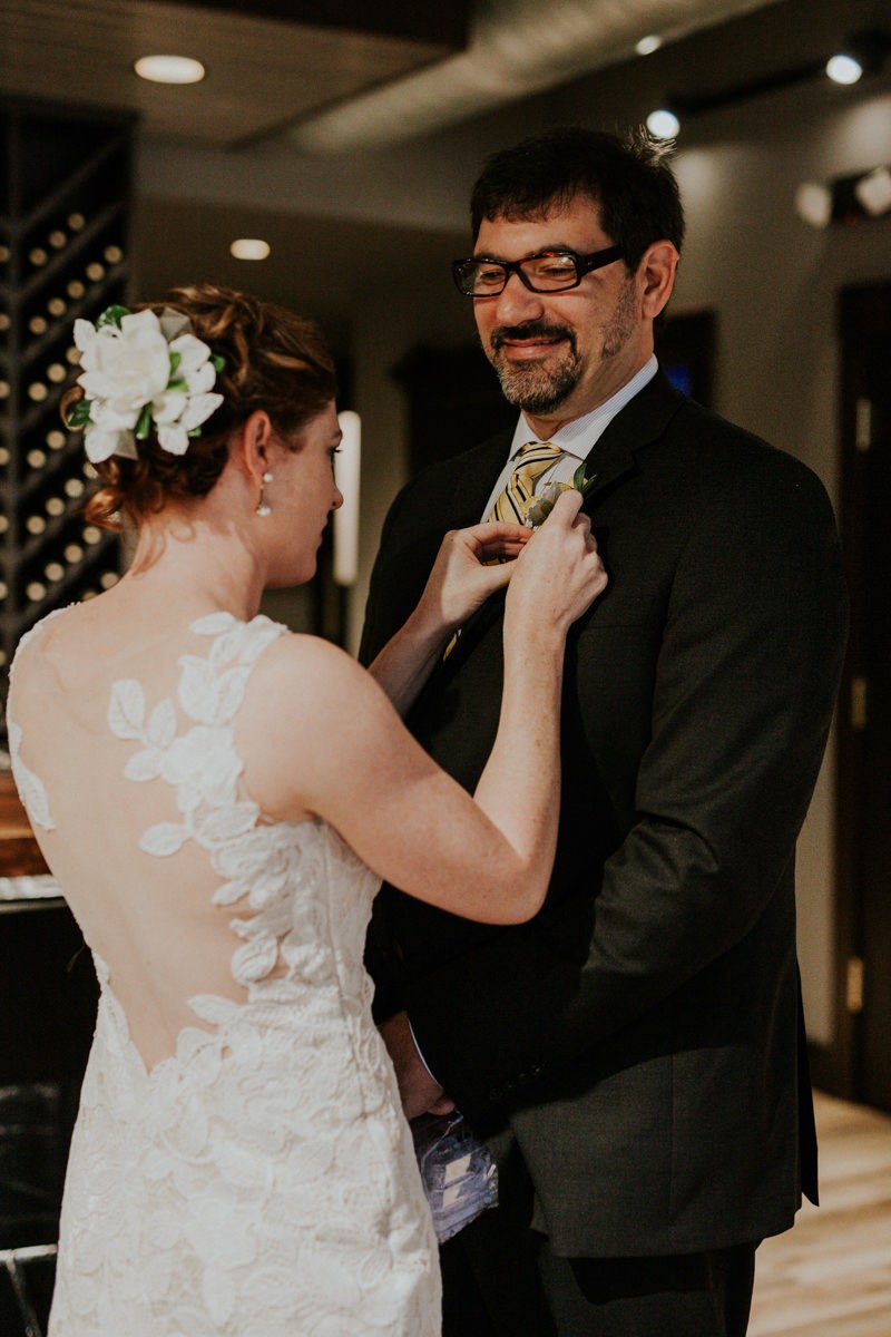 Bride places a boutonniere on Groom's lapel. 