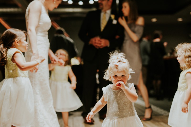 Darling flower girls dance at a modern indoor wedding reception. 