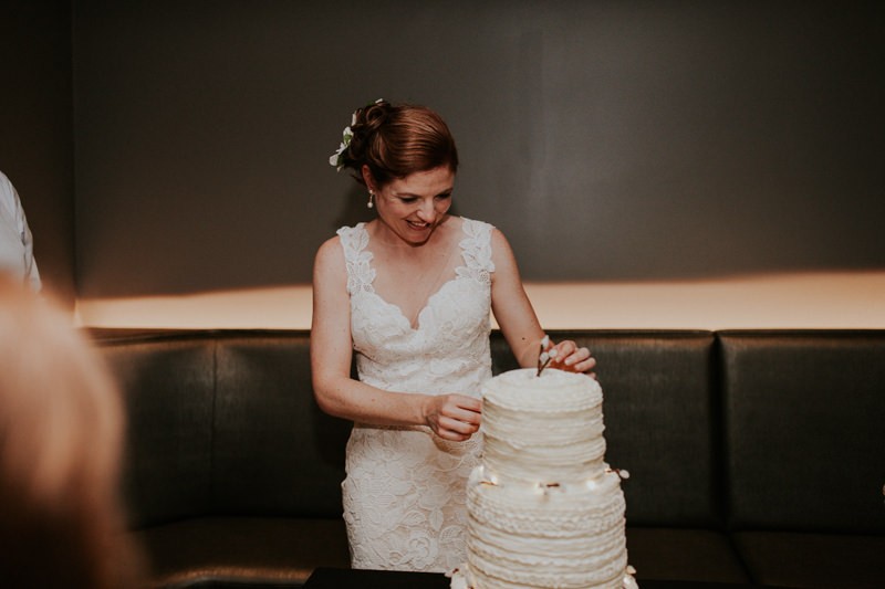 Bride removes Pussy Willow cake topper and string lighting from her wedding cake. 