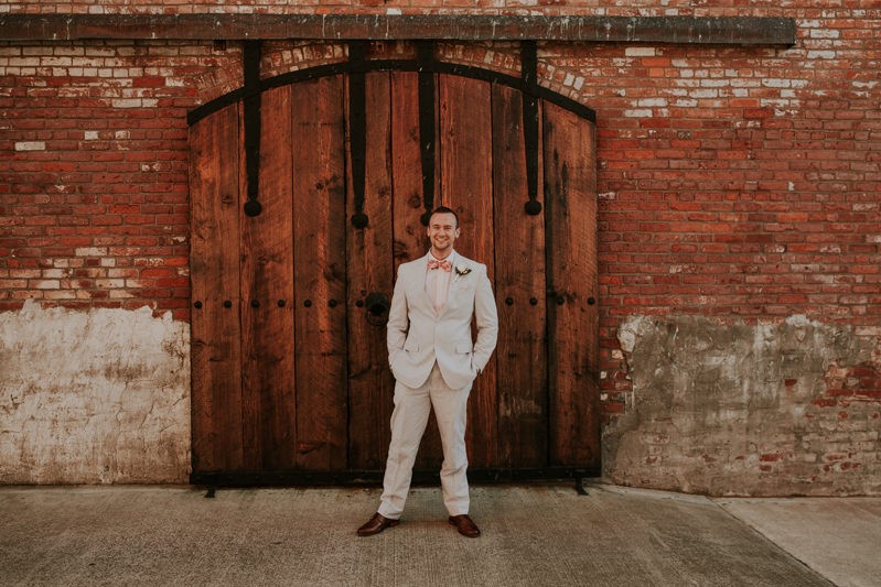 Groom with Southern Charm, wearing a blue seersucker suit and coral bow tie in Port Townsend, WA. 