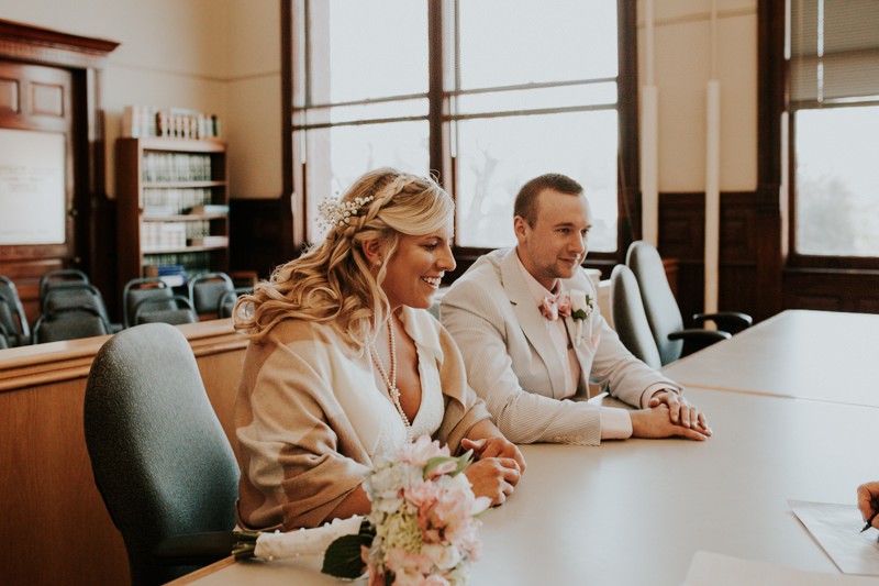 Courthouse wedding, with bride in a lace v-neck dress and groom wearing a suit and bow tie. 
