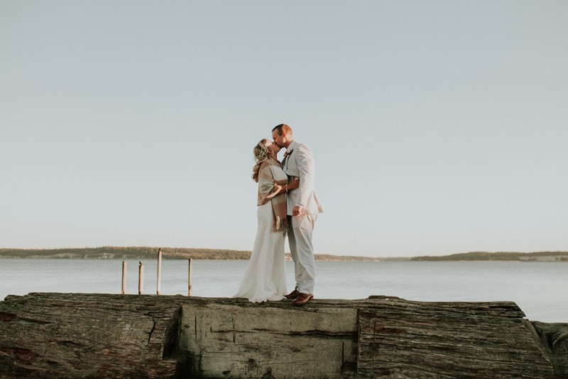 Romantic elopement on the Port Townsend waterfront, with bride in a floor-length gown, and groom in a light suit. 