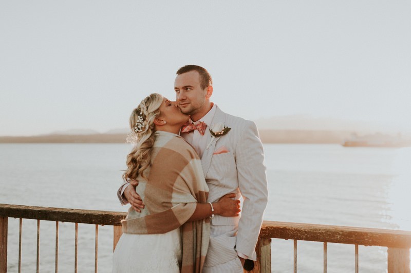 Romantic sunset elopement in Port Townsend, with groom in a blue seersucker suit and coral bow tie. 