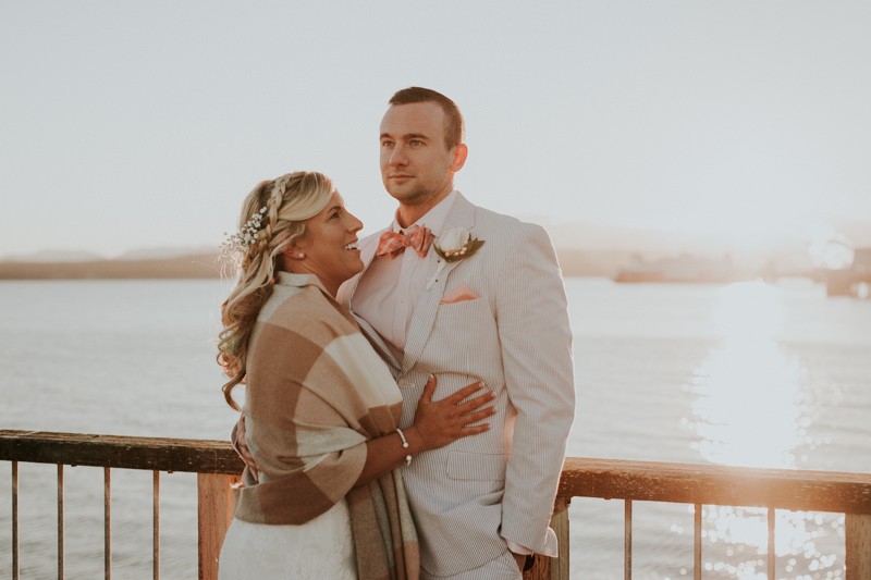 Groom in a seersucker suit and bride wearing a tan shawl at sunset in Port Townsend. 