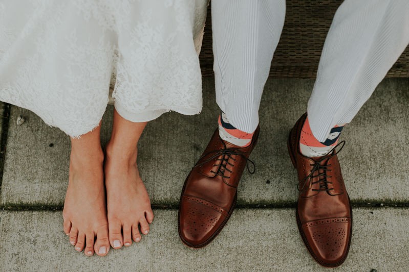 Quirky wedding couple at the Port Townsend waterfront, with barefoot bride, and groom wearing brown oxfords. 