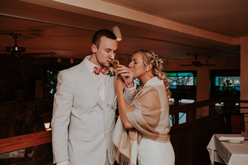 Groom in a blue seersucker suit and coral bow tie, with bride wearing a tan shawl. 