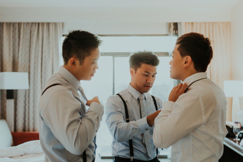 Groomsmen helping groom with tie, getting ready at the Hilton Bellevue. 