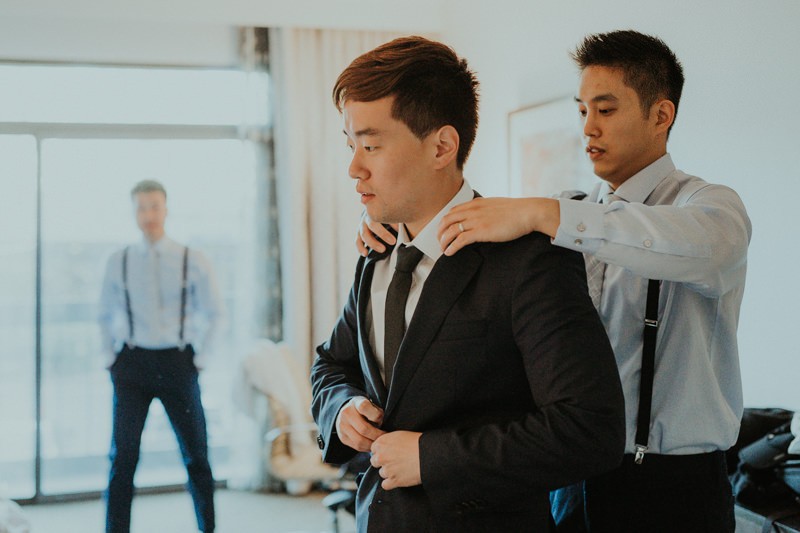 Groom getting ready at the Hilton Bellevue, with a blue jacket and black skinny tie. 