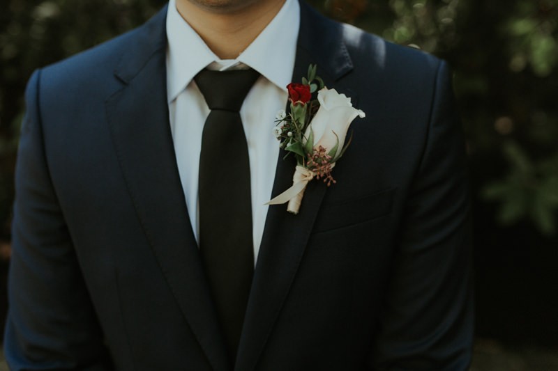 White rose boutonniere on groom in a navy suit, at Robinswood House. 