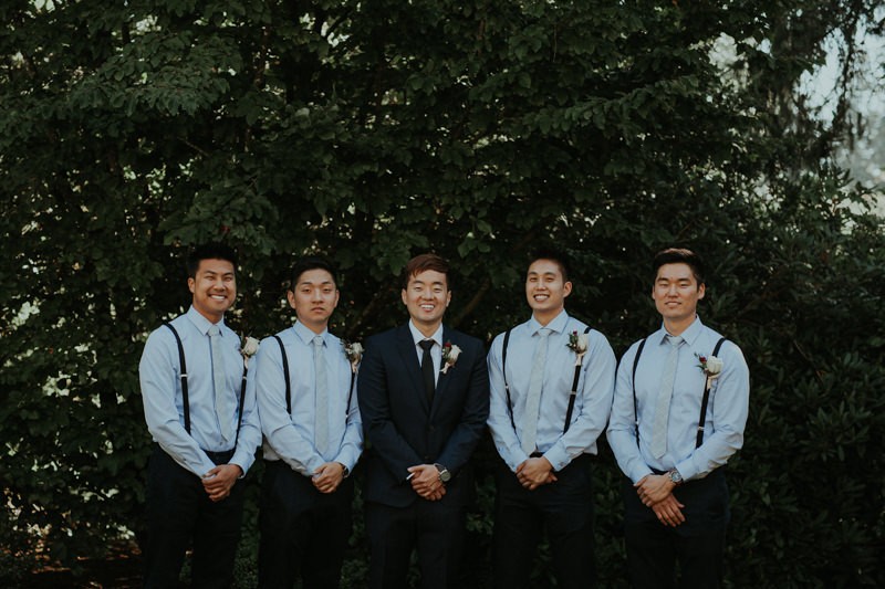 Modern wedding with groomsmen wearing light blue shirts and suspenders. 