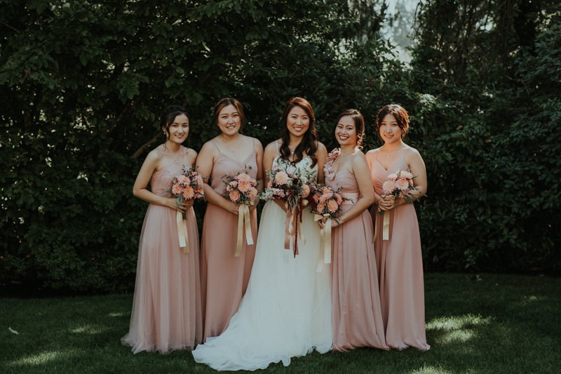 Romantic wedding details, with bridesmaids in soft pink flowing dresses. 