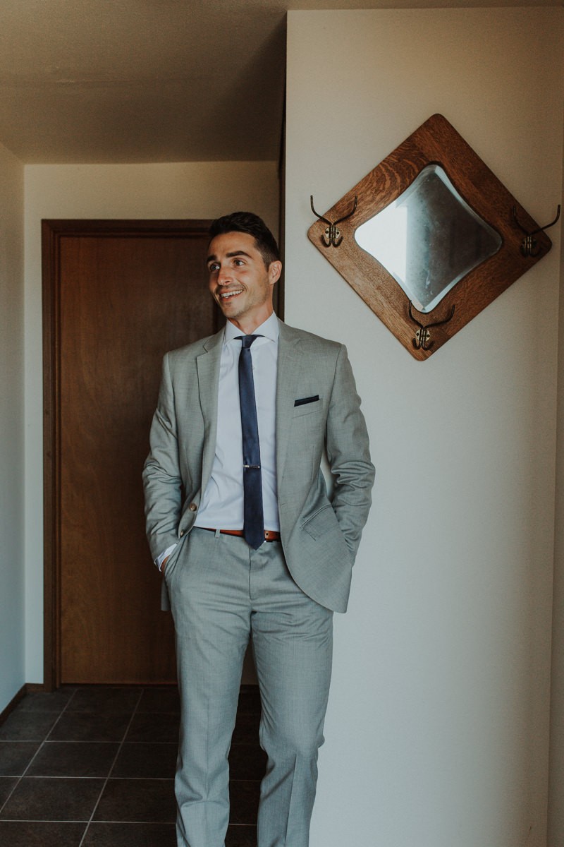 Groom in a modern grey suit, with blue pocket square and skinny tie. 