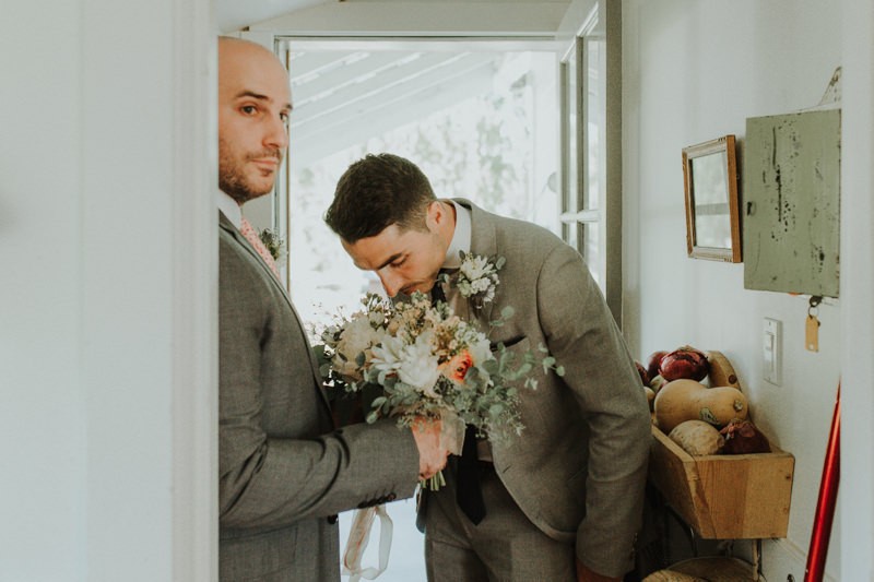 Groom smells handmade floral bouquet for bride. 