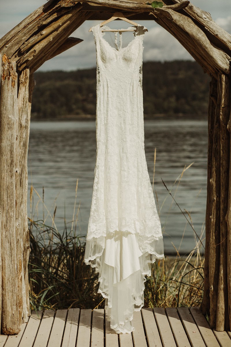 Beautiful illusion-back lace wedding gown hanging from wedding arch at The Edgewater House | Seattle wedding + elopement photographer Meghann Prouse | www.photomegs.com