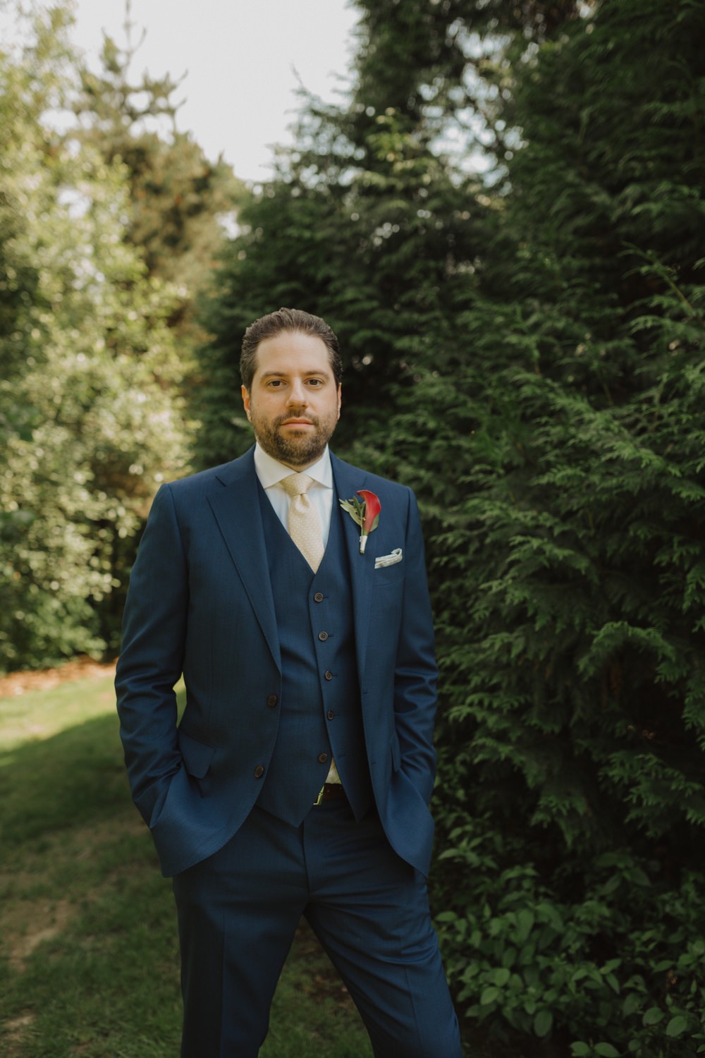 Groom in a navy suit and vest, with cream tie and calla lily boutonniere. 