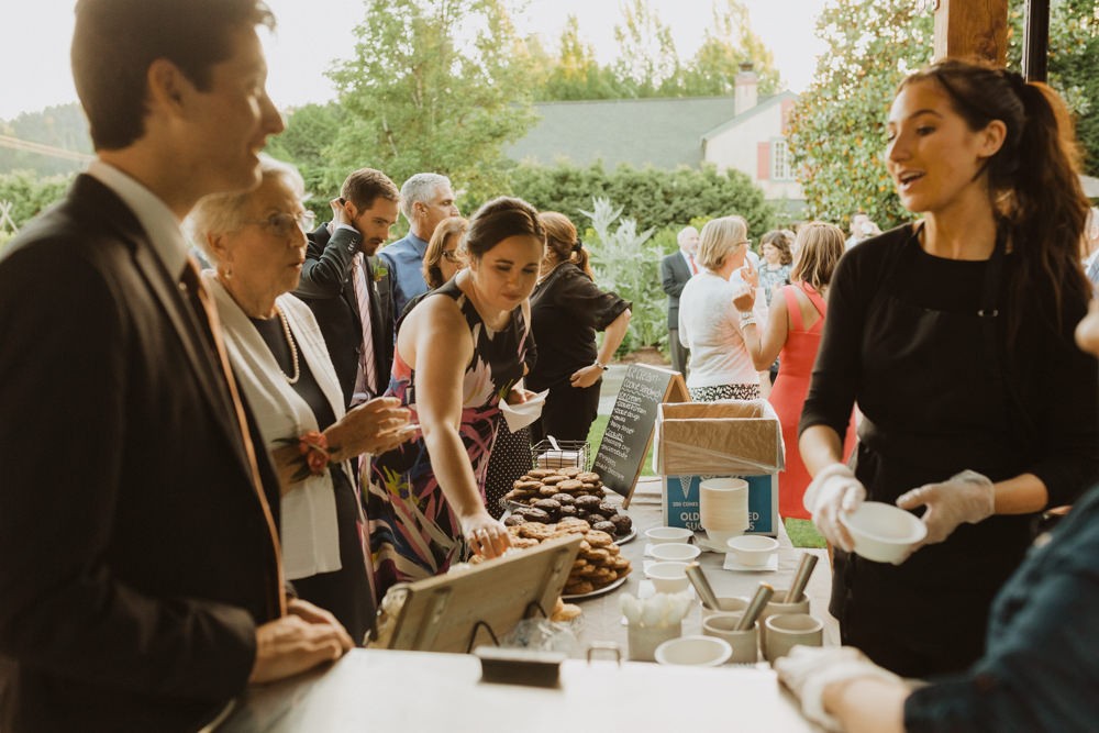 Guests order treats from ice cream cookie sandwich bar at Willows Lodge wedding. 