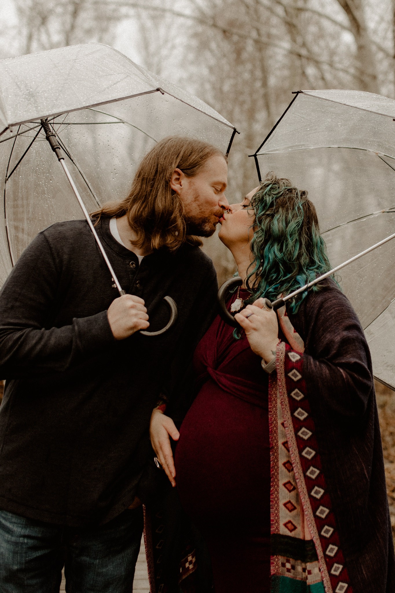 Alternative, punk parents-to-be in the rain with clear bubble umbrellas for a rainy maternity session in Kitsap County, Washington. 