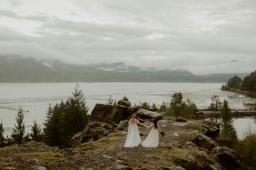 Same-sex eloping couple on a bluff overlooking the Columbia River on a foggy, misty day. 