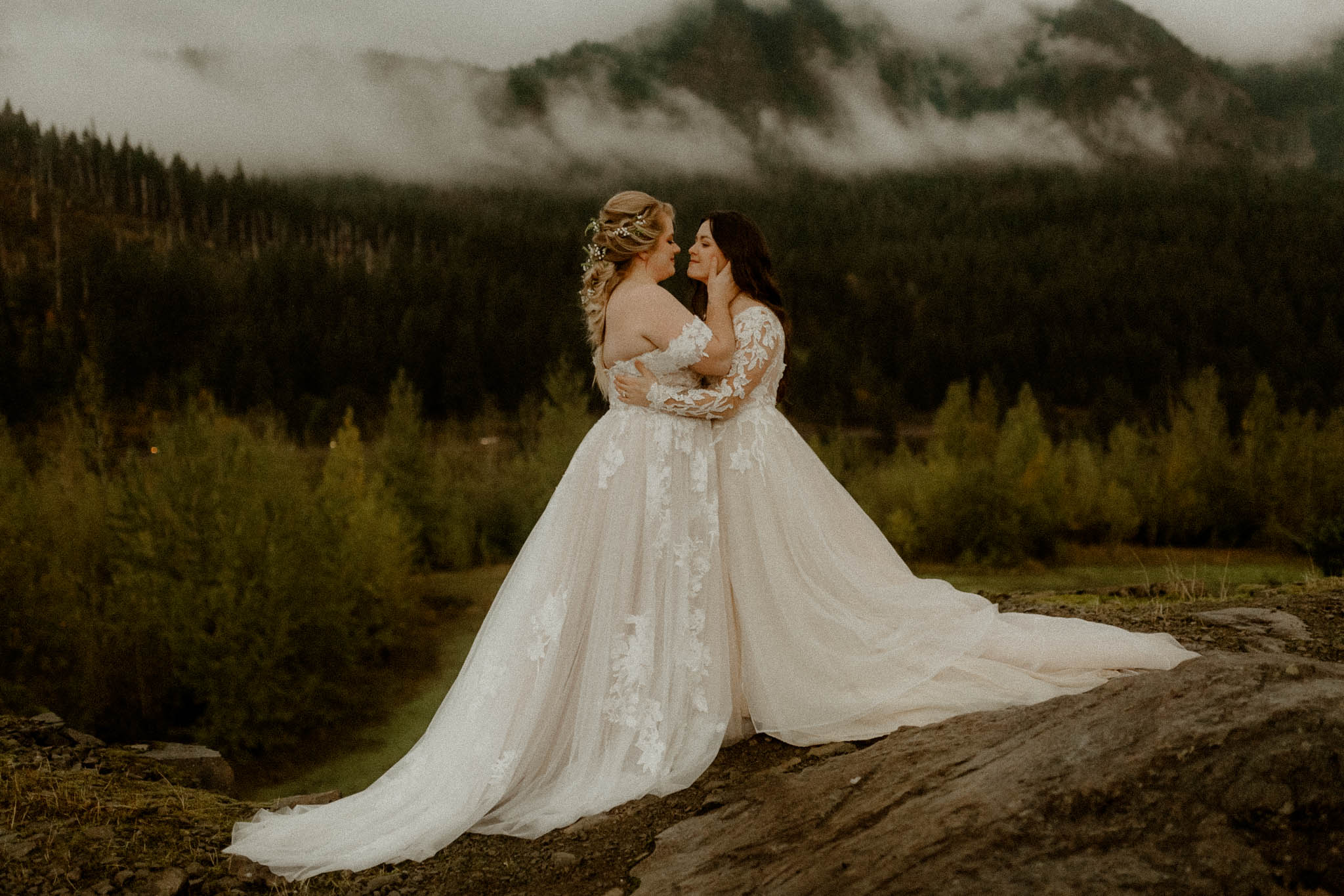 Moody same-sex elopement in the PNW on a rainy day, with fog covering the mountains in the background. 