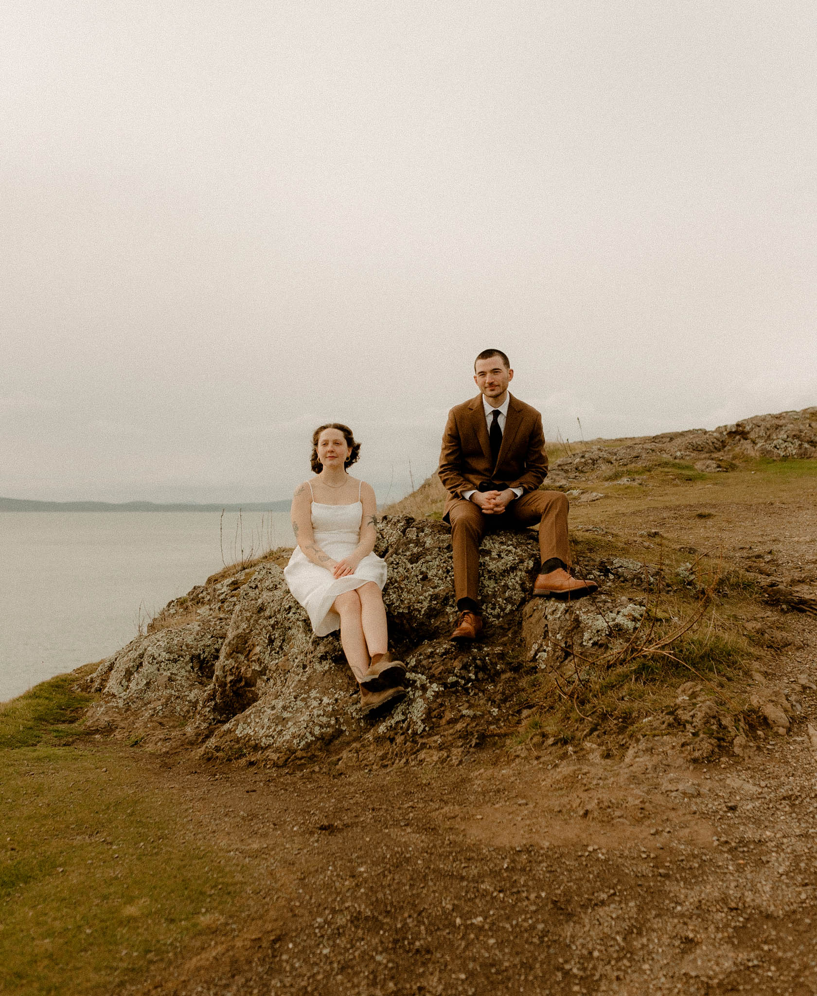 Rosario Head elopement photos, with one partner in a brown suit and the other in a simple strappy white dress. 