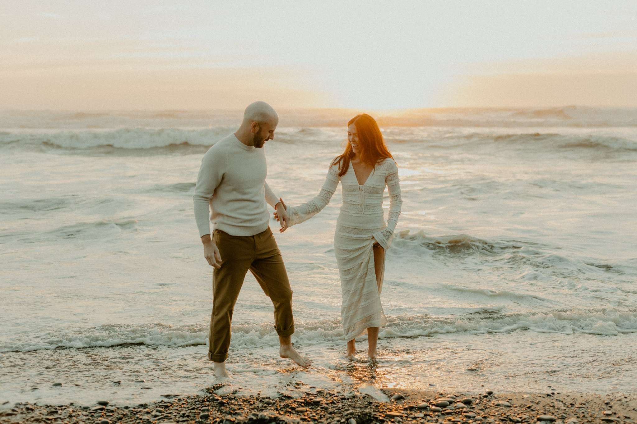 Engaged couple walking in the waves at sunset in Forks Washington